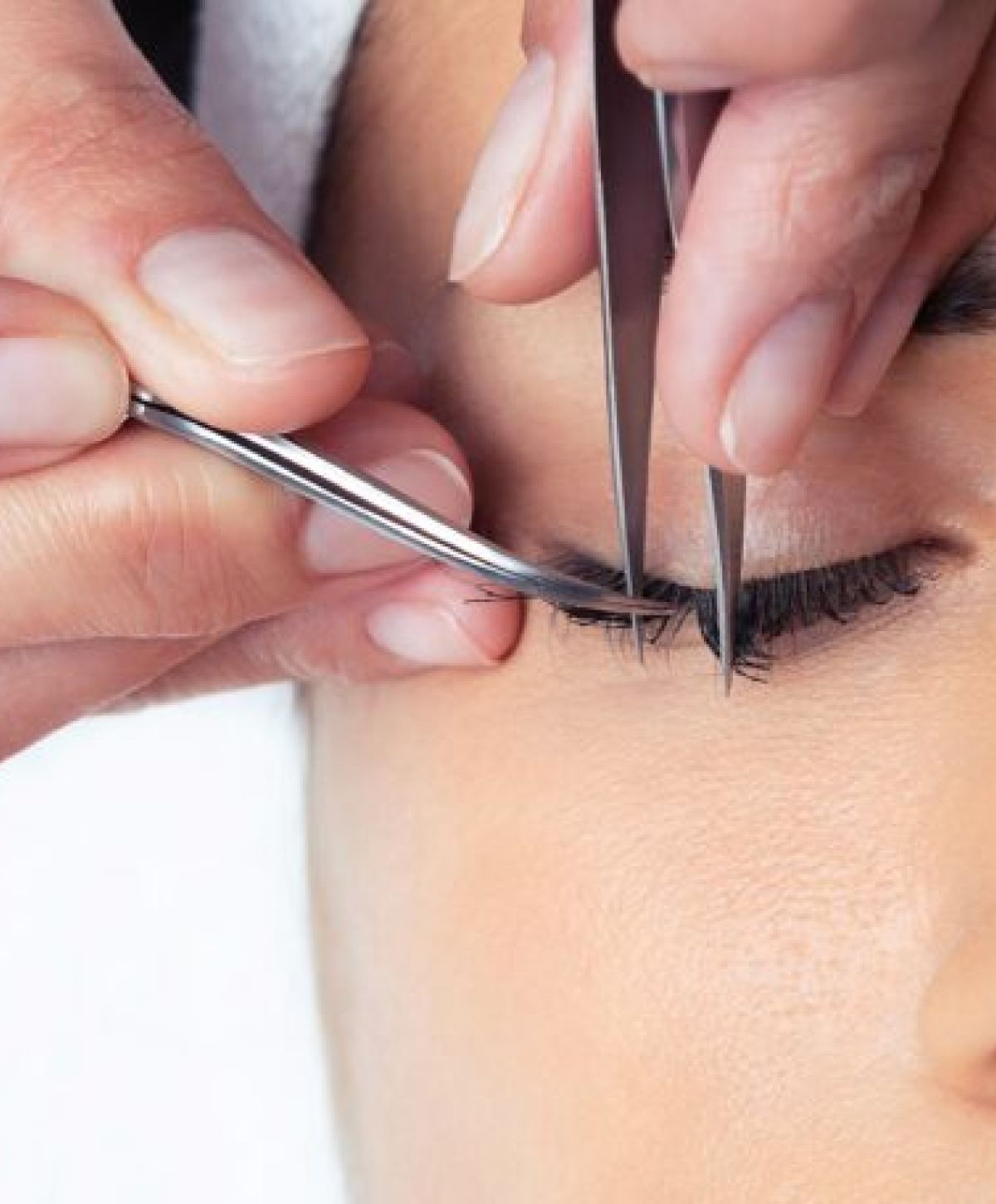 Applying eyelash extensions with precision tools.
