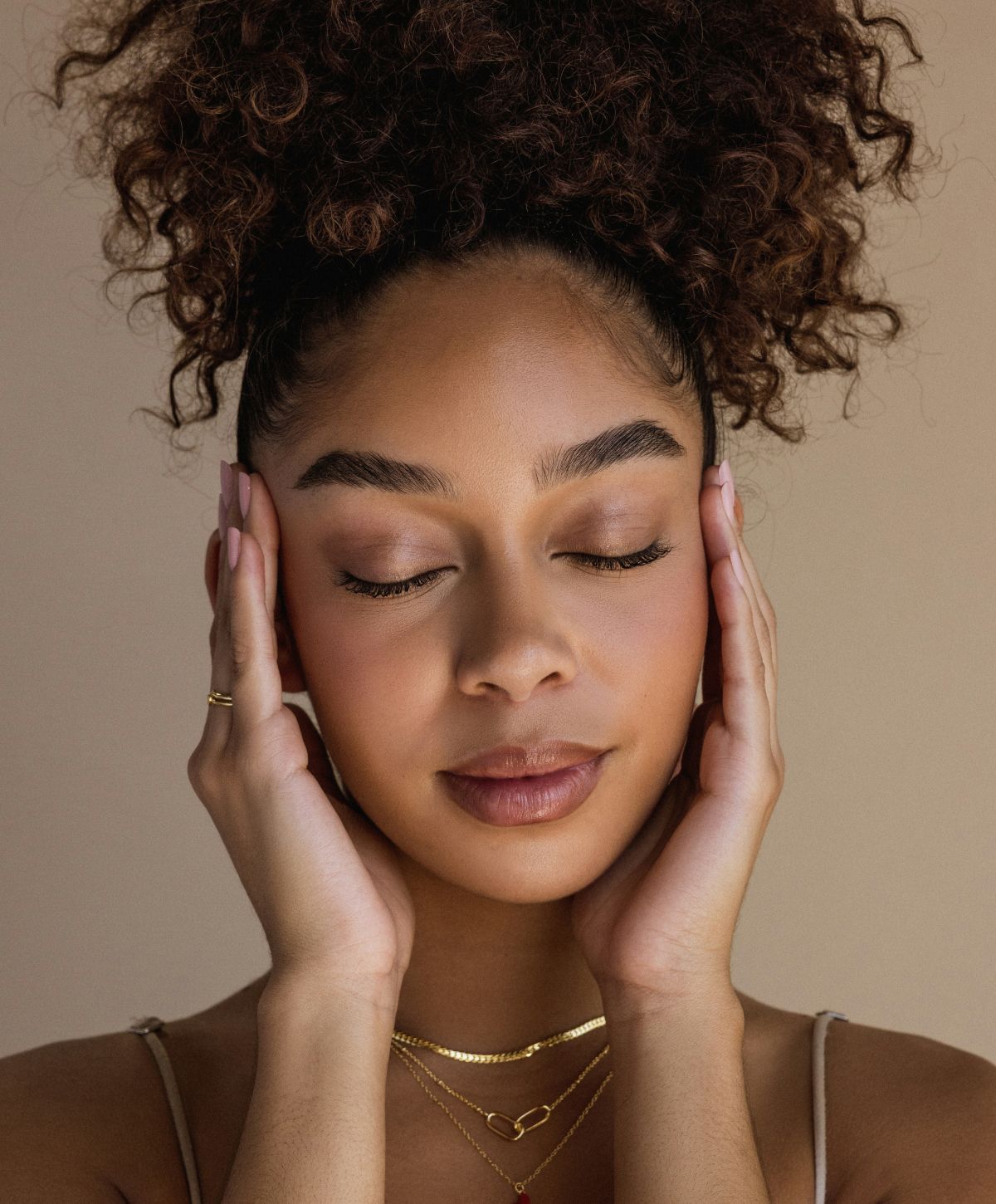 Woman with curly hair, eyes closed, serene expression.
