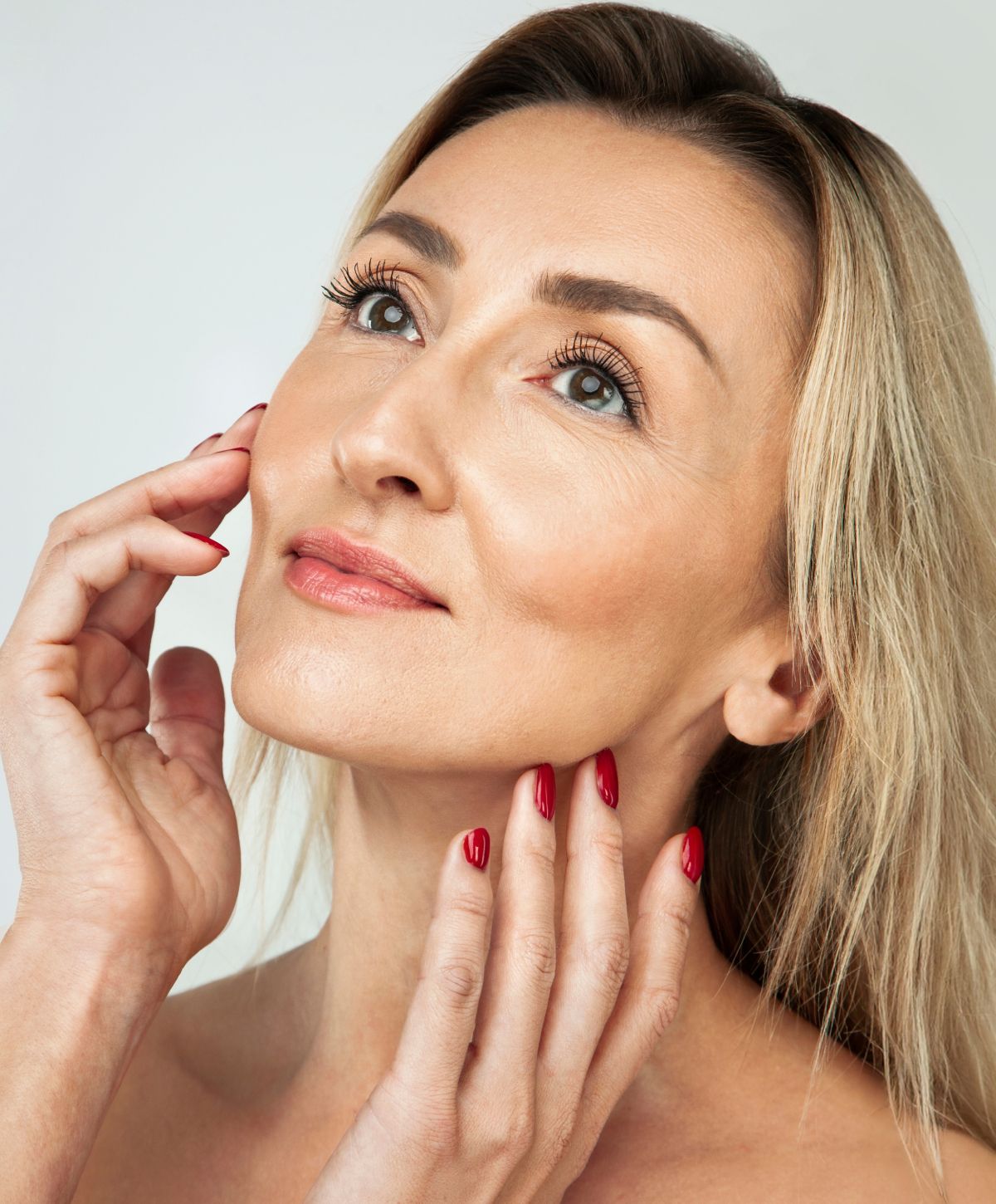 Woman with blonde hair touching her face.