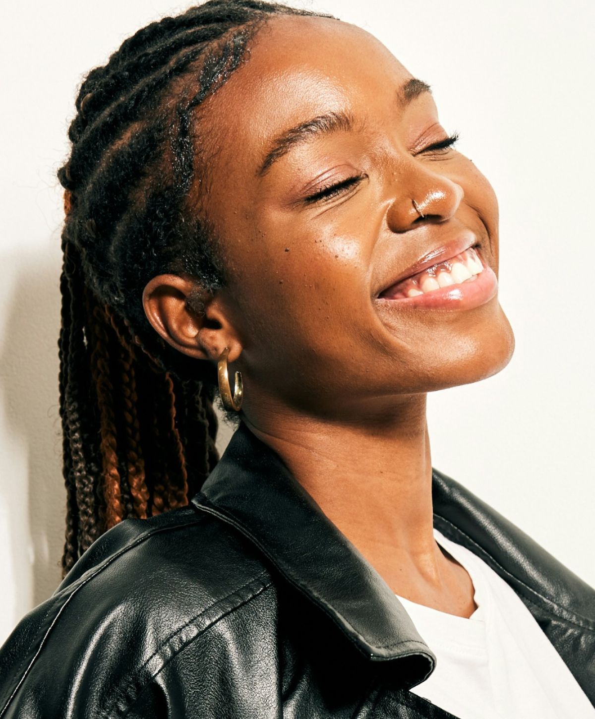Woman smiling, wearing a leather jacket, braided hair.