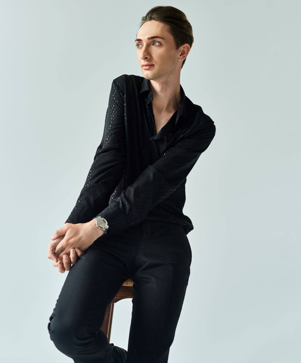 Person in black shirt posing against light background.