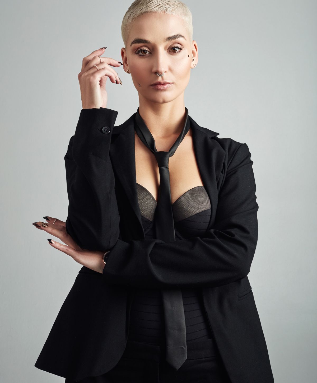 Person in a black suit and tie, posing confidently.